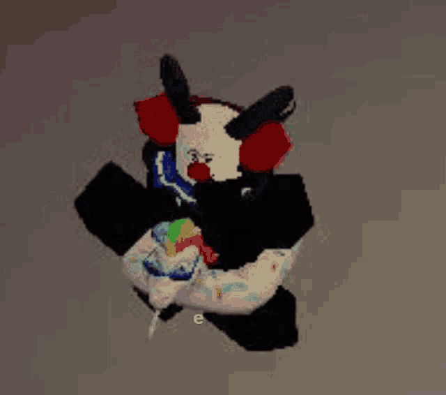 a clown with horns is holding a rainbow colored lollipop in his hand .