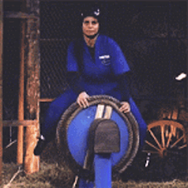 a woman in a blue uniform is riding a blue barrel