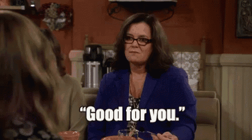 a woman in a blue jacket and glasses is sitting at a table and saying good for you .