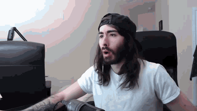 a man with long hair and a beard wearing a black hat