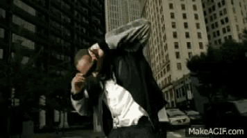 a man in a suit and tie is doing a dab in front of a city skyline .