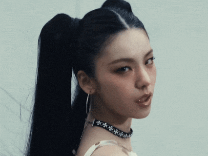 a close up of a woman 's face with her hair in a ponytail and a choker .