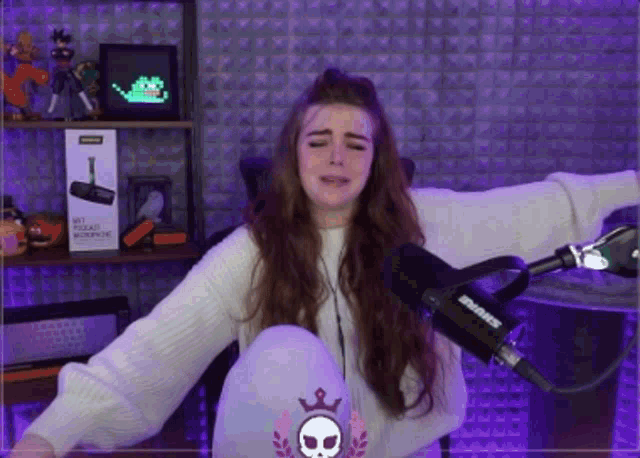 a woman is sitting in front of a shure microphone with her arms outstretched