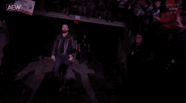 a man in a leather jacket holding a wrestling championship belt with the name jon moxley on it