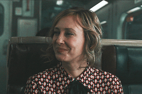 a woman sitting on a train with her eyes closed and a patterned shirt on