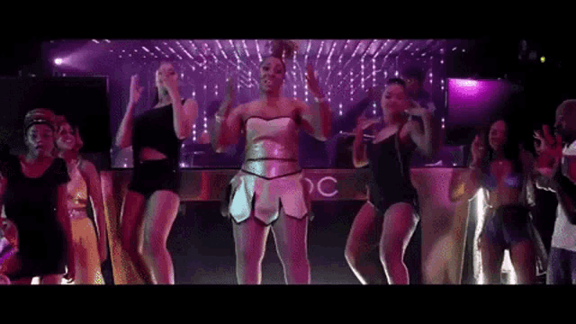 a group of women are dancing on a stage in front of a sign that says c.