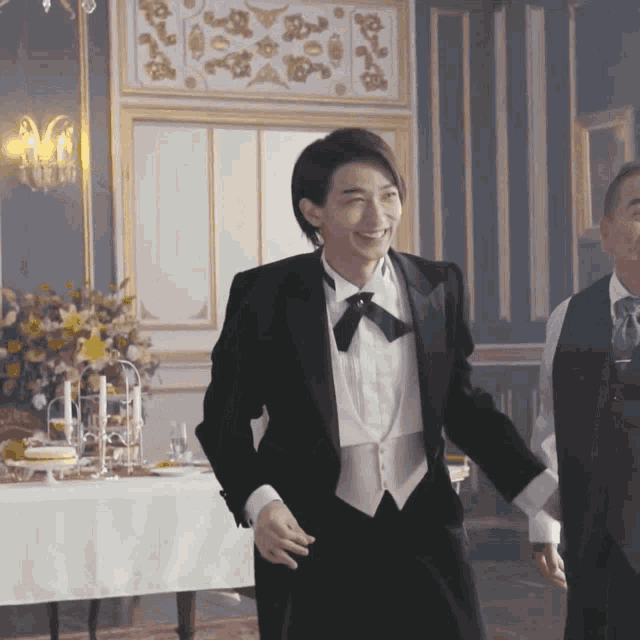 a man in a tuxedo and bow tie is dancing in a room