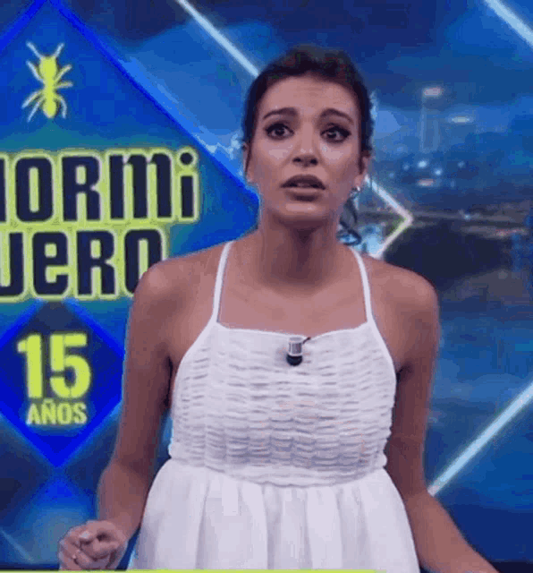 a woman in a white dress stands in front of a sign that says 15 años