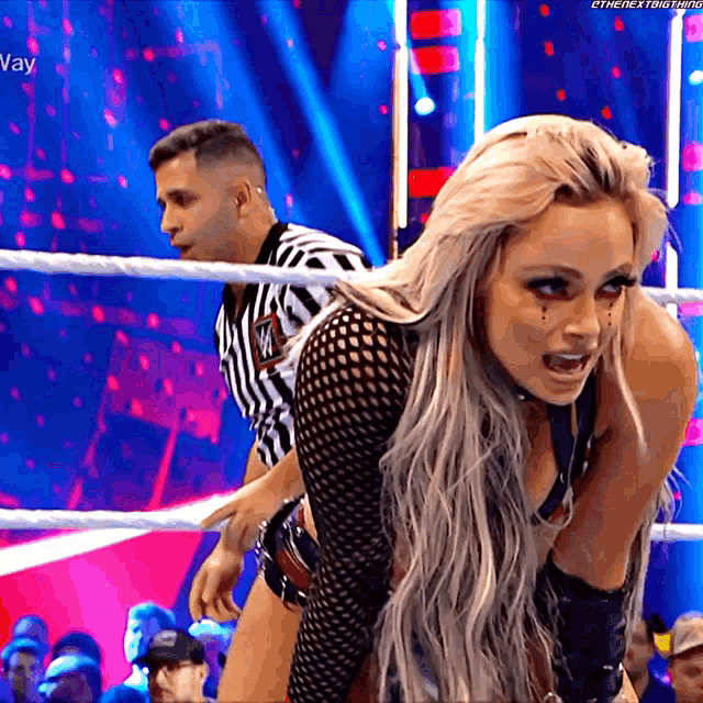 a woman in a wrestling ring with a referee in the background .