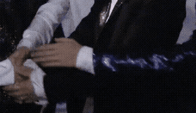 two men are shaking hands in a dark room .