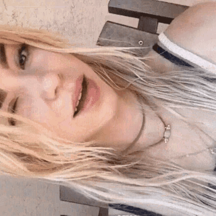 a woman with long blonde hair is wearing a necklace
