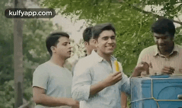a group of men are standing around a blue cooler .