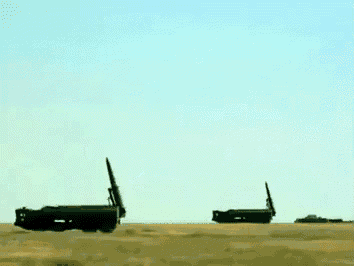 a row of cannons in a field with a blue sky behind them