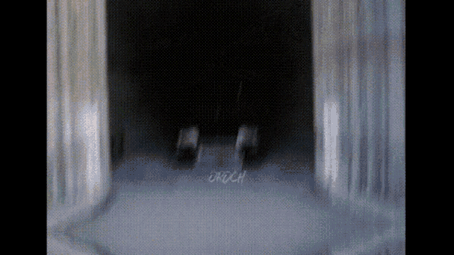 a blurred image of a person standing in a dark room with the word crunch written on the floor .