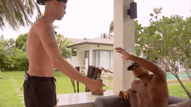 a shirtless man is standing next to another shirtless man on a porch