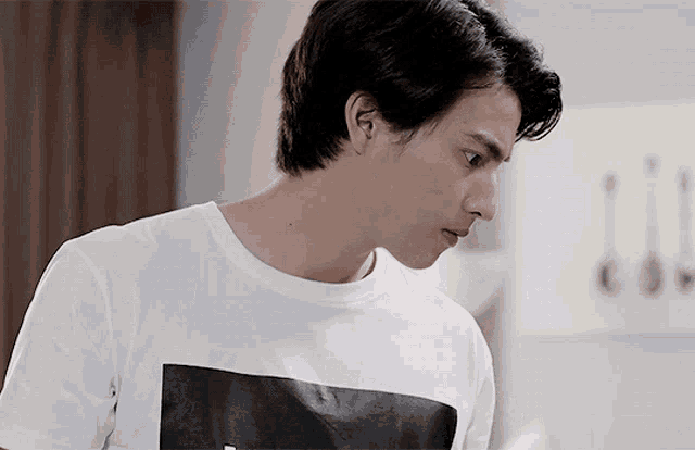 a young man wearing a white t-shirt with a black graphic on it