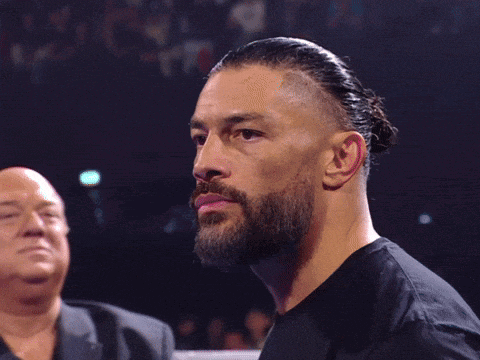 a man with a beard in a black shirt stands in front of a man in a suit