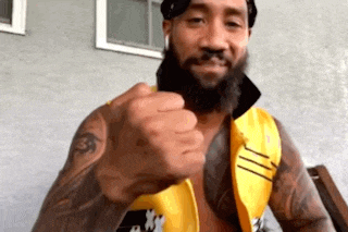 a man with a beard and a yellow vest is making a fist .