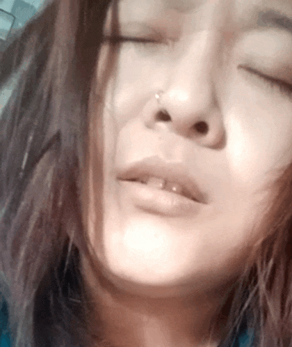 a woman with her eyes closed has a nose ring in her nose