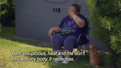 a woman in a purple shirt is sitting in a chair and covering her face with her hand while a cat watches