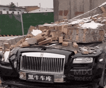 a rolls royce is sitting in a pile of bricks next to a mix videos sign