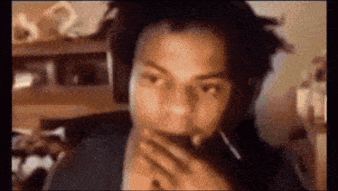 a man wearing headphones is covering his mouth with his hand while talking on a video call .