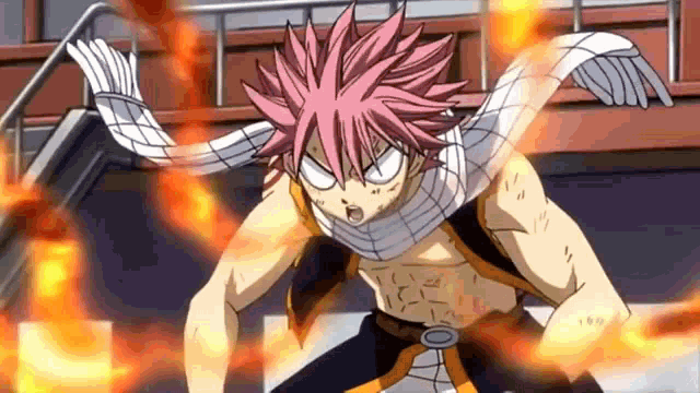 a man with pink hair and a scarf around his neck is standing in front of a building with fire coming out of his chest .
