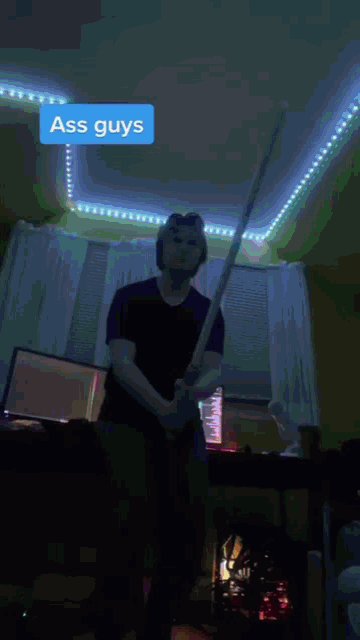 a man holding a sword in a dark room with a sticker that says " ass guys "