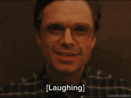 a close up of a man wearing glasses and a plaid shirt is laughing .