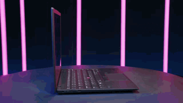a laptop is open and sitting on a table in front of purple lights