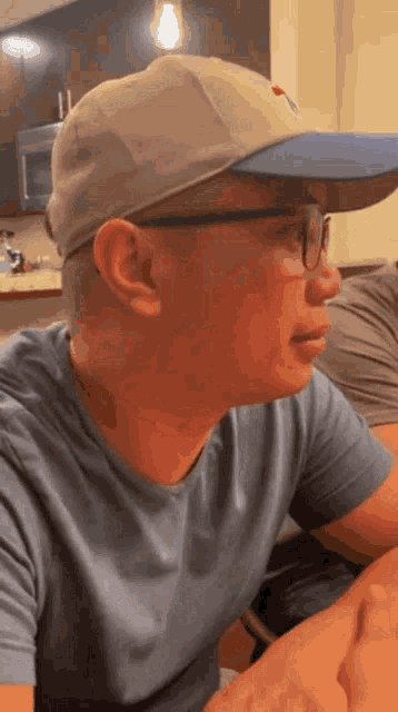 a man wearing a baseball cap and glasses looks to his left