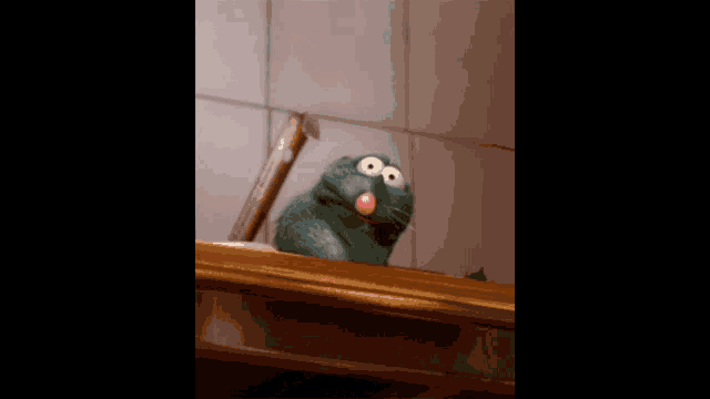 a stuffed animal with a pink tongue sticking out is sitting on a shelf