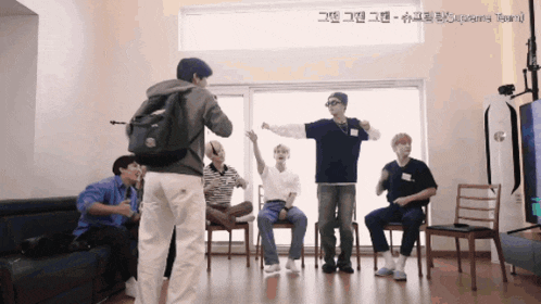 a man with a backpack is taking a picture of a group of young men dancing