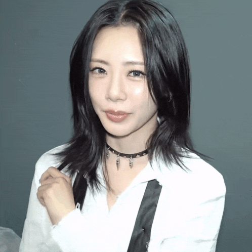 a woman wearing a choker and a white shirt is smiling