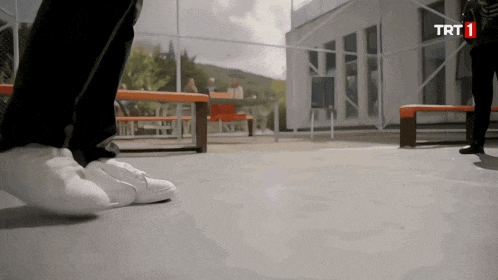 a person 's feet are shown in front of a building that has trt1 on it