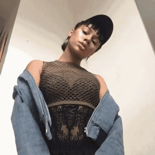 a woman wearing a denim jacket and a fishnet top