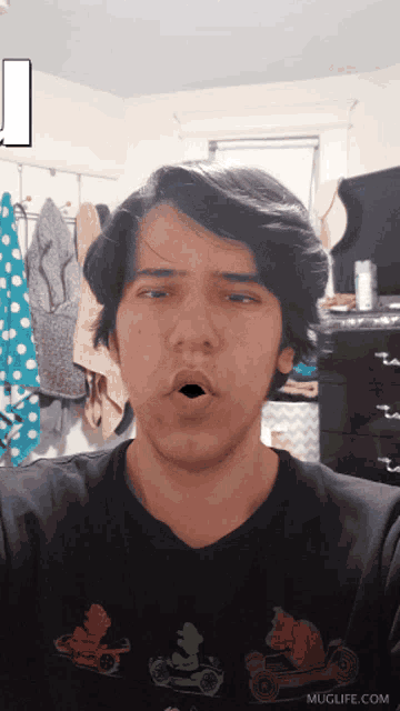 a man wearing a black shirt that says muglife.com makes a funny face