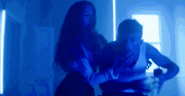 a man and a woman are dancing in a dark room in front of blue lights .