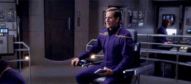 a man in a purple uniform is sitting on a chair and waving