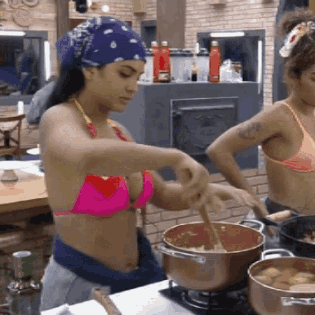 a woman in a pink bikini is stirring a pot with a wooden spoon