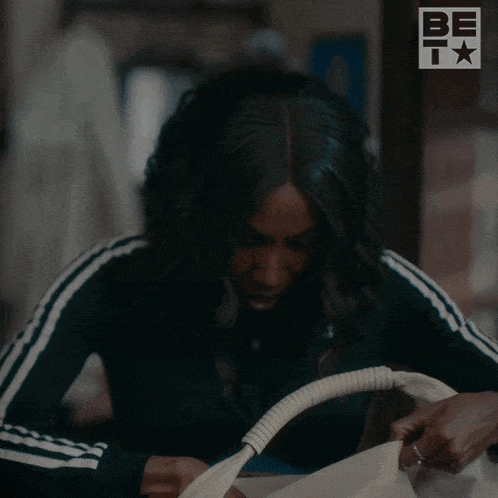 a woman in a black adidas jacket holds a bag
