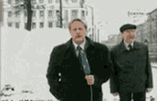a man holding a microphone stands next to another man in the snow