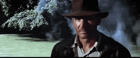 a man wearing a hat and a leather jacket looks at the camera