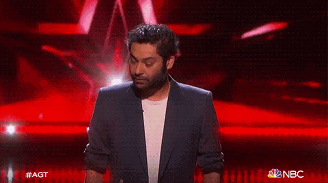 a man with a beard on a stage with a nbc logo in the corner