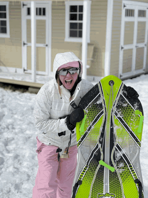a woman wearing a pink hat and sunglasses is holding a sled in the snow
