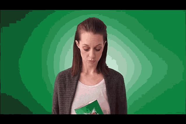 a woman in a grey cardigan is holding a green bag that says ' christmas ' on it