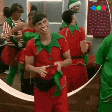 a man in a red and green elf costume is standing in front of a mirror