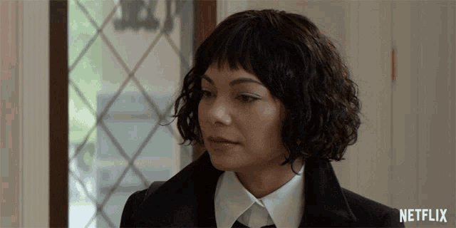 a woman with curly hair is wearing a netflix logo on the bottom right