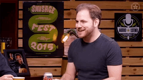 a man is sitting in front of a sausage fest 2015 sign