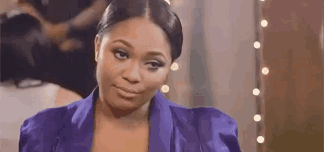 a woman in a purple jacket is making a funny face and smiling .